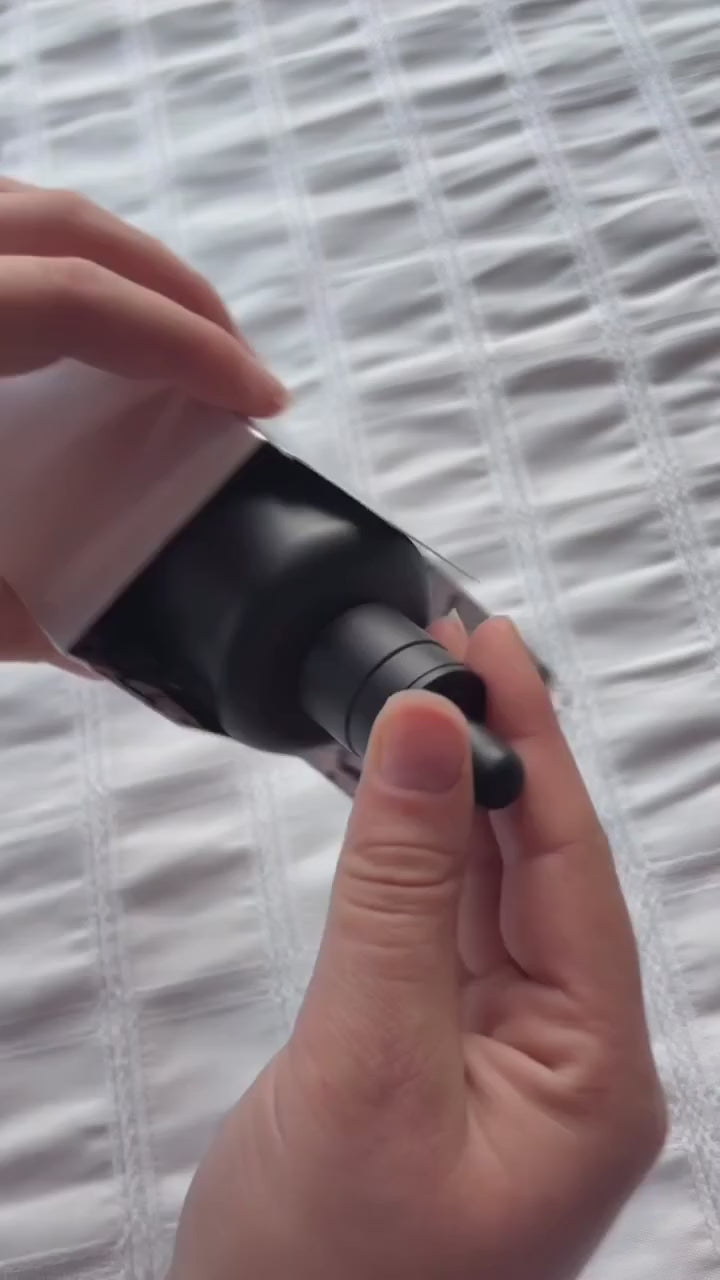 Close-up video of MASIL Scalp Serum For Hair Loss showing hands opening a matte black dropper bottle, lifting the pipette to reveal the clear lightweight formula, and presenting the product with its packaging in the background.