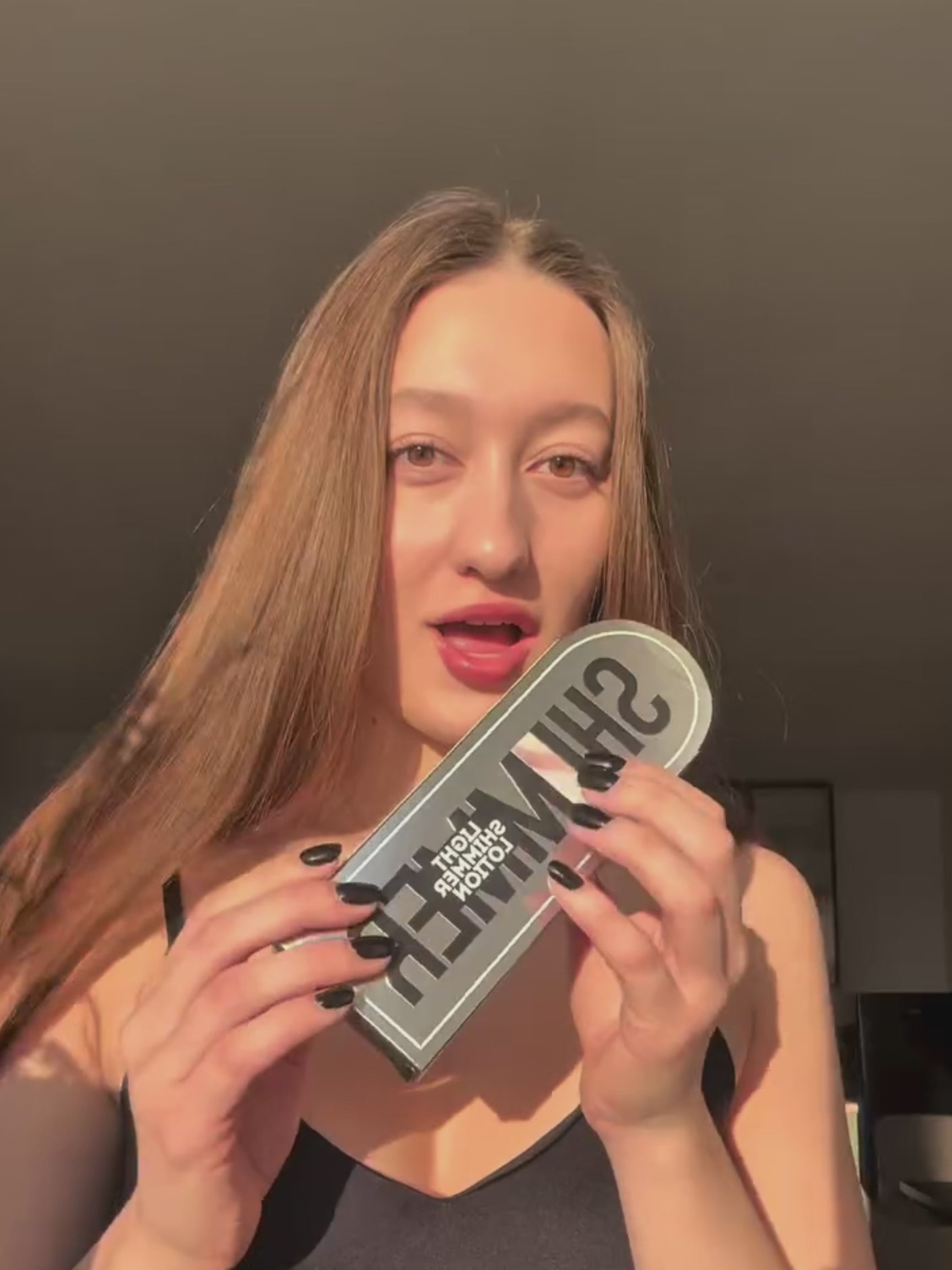 A long-haired influencer in a black camisole applied cffinder body shimmer to her collarbone, contrasting the soft-focus highlight of the treated area with its previous dullness.